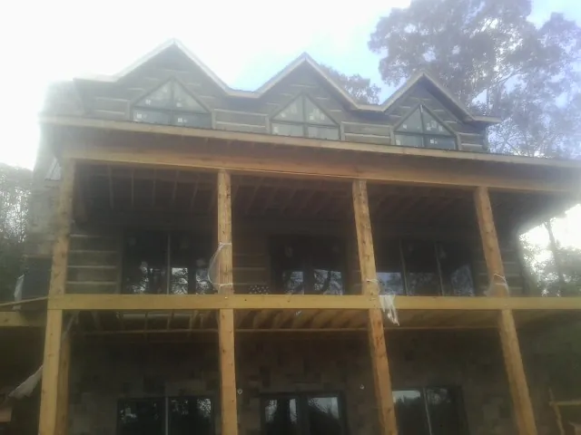 Dormers and porch framing on a large log home under construction — Roof Coating work by our crew in Columbia Falls