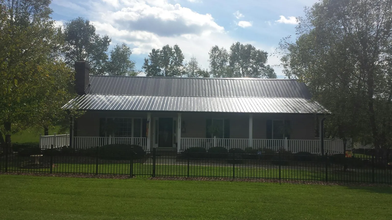 Gray metal roof on a brick ranch with a full width front porch — Gutter Guard Installation work by our crew in Columbia Falls