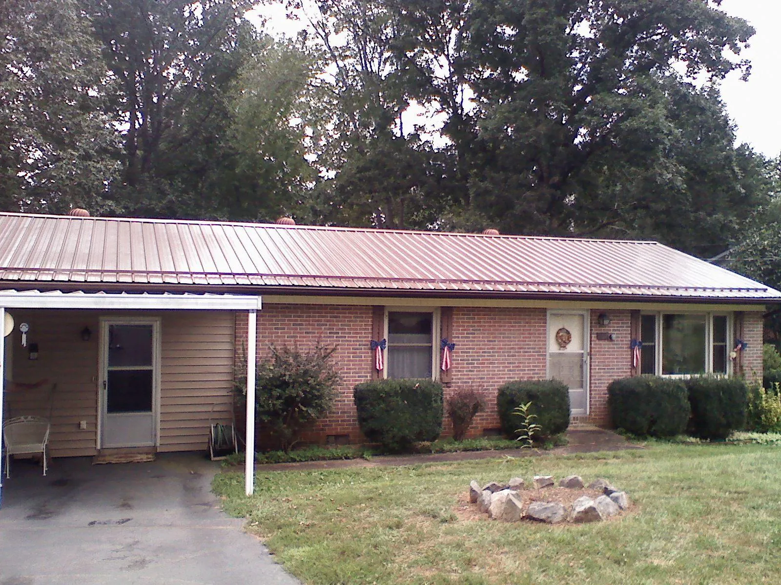 Bronze metal roof and carport on a brick ranch home — Roof Repair work by our crew in Columbia Falls